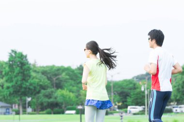 Sportif genç Asyalı çift parkta koşuyor.