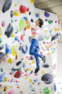 Güzel Japon kadın spor salonunda duvara tırmanıyor. 