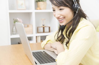 Laptop kullanan kulaklıklı genç Asyalı kadın. 