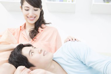 Asyalı erkek ve genç kadın kanepede. 