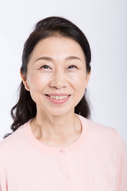 Beyaz arka planda yalnız gülümseyen Asyalı son sınıf öğrencisi kadın. 