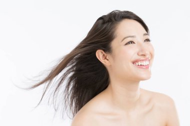 Uçan rüzgâr saçlı mutlu genç kadın beyaz arka planda izole edilmiş.