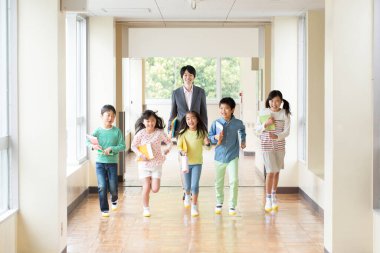 Öğretmenli bir grup Japon çocuk okul koridorunda yürüyor. 