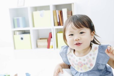 Evdeki oturma odasında oynayan tatlı Asyalı küçük kız.