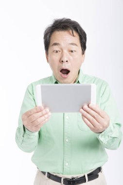 Beyaz arka plana karşı tabletli olgun Japon adamın stüdyo fotoğrafı.