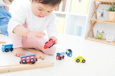 Bebek renkli oyuncak trenlerle oynuyor.