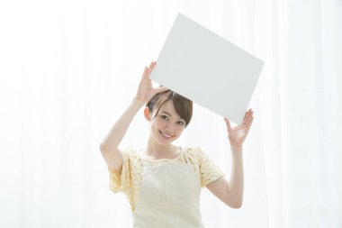 Mutfakta elinde boş tabela olan Asyalı genç ev kadınının portresi..