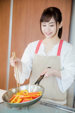 Genç Japon kadının portresi mutfakta yemek hazırlıyor. 