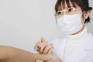 Doktor hastaların eline iğne yapıyor. 