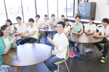 Genç Asyalı öğrenciler sınıfta akıllı telefon kullanıyorlar.