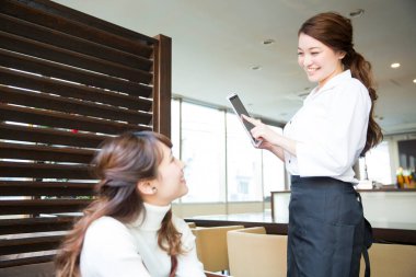 Güzel Japon garson restoranda tabletle sipariş veriyor.