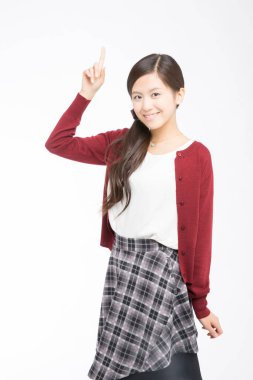 Genç Asyalı kadın beyaz arka planı işaret ediyor.