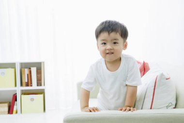 Asyalı çocuk evde, kanepede.