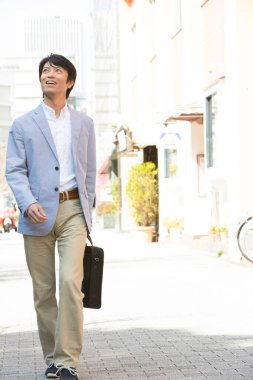 Asyalı mutlu iş adamı sokakta yürüyor