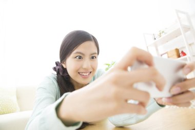 Asyalı kadın akıllı telefonuyla selfie çekiyor.