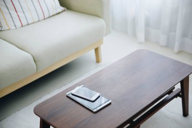 Akıllı telefon ve tablet oturma odasında, tahta bir masanın üstünde.