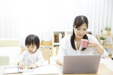 Anne dizüstü bilgisayarla ve bebek çizimiyle çalışıyor. 