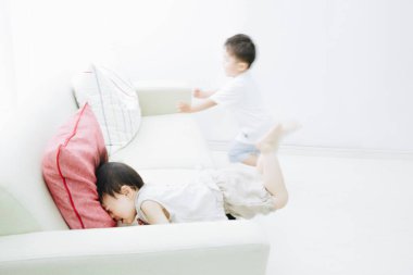 Asyalı çocuk kız kardeşiyle kanepede oynuyor. Oturma odasında, mutlu bir aile, konsept.