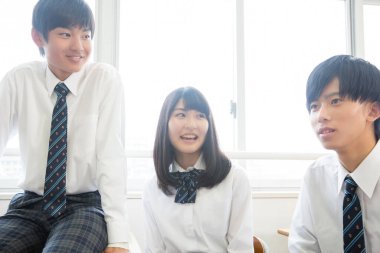 Üniformalı öğrenciler sınıfta konuşuyor.