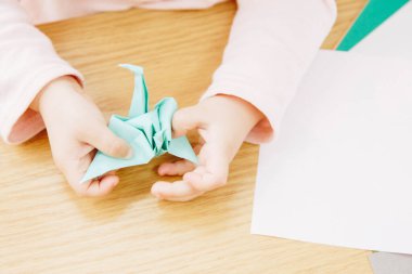 Çocuğun elleri origami kağıdı yapıyor. Kapat..