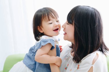 Evdeki oturma odasında annesiyle oynayan tatlı Asyalı küçük kız.