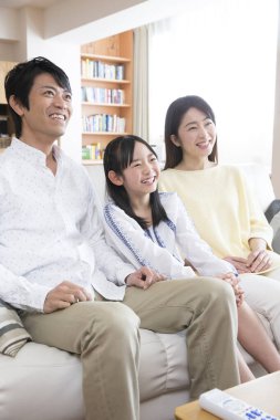 Mutlu bir ailenin portresi kanepede oturup televizyon izliyor. 