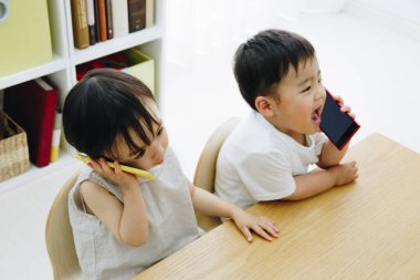 Asyalı çocuklar evde akıllı telefonlardan konuşuyor. 