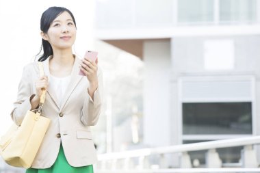 Şehirde cep telefonu olan Asyalı genç bir iş kadını.