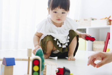 Küçük tatlı Japon kız oturma odasında oyuncaklarla oynuyor.