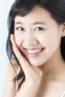 Asyalı genç bir kadının portresi elleriyle yüzüne dokunuyor.