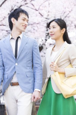 Parkta çiçek açan sakura ağaçları olan genç Asyalı çift.