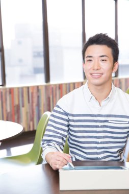 Genç Asyalı adam çizim için dijital tablet kullanıyor 