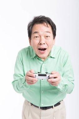 joystick 'i tutan yaşlı Asyalı adam, stüdyo fotoğrafı. 