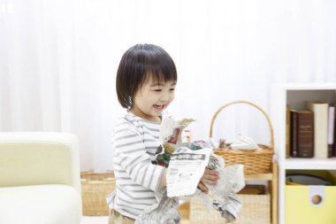 Elinde gazete tutan Asyalı küçük kız. 