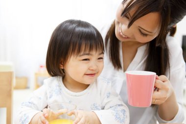 Mutlu Asyalı anne ve küçük kız kahvaltı yapıyor. 