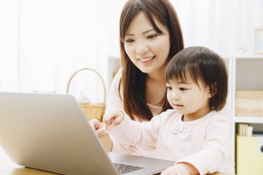 Güzel Asyalı anne ve kızını dizüstü bilgisayarla kapat.
