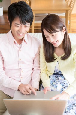 Çift evdeki oturma odasında dizüstü bilgisayar kullanıyor.