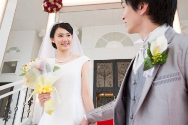 Merdivenlerde poz veren mutlu Asyalı gelin ve damadın portresi.