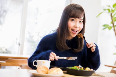 Güzel genç bir kadın Japon restoranında öğle yemeği yiyor.