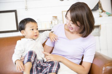 Kahverengi koltukta oturan kadın ve çocuk gülümsüyor.