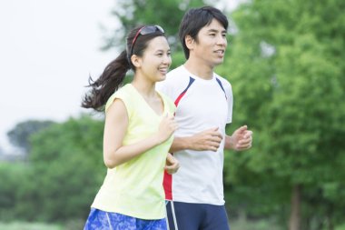 Sportif genç Asyalı çift parkta koşuyor.