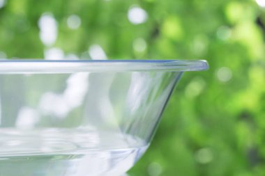 Yaz bahçesindeki beyaz masada temiz su dolu cam kase.