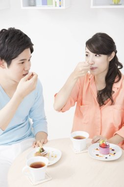 Genç çift mutfakta kek yiyor.