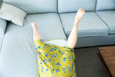 Kanepeden düşen Asyalı genç kadın. 