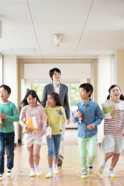 Öğretmenli bir grup Japon çocuk okul koridorunda yürüyor. 