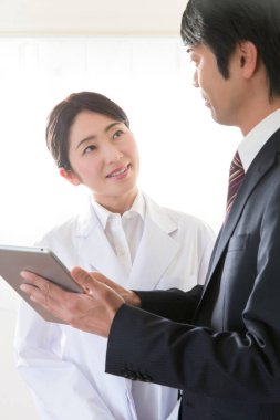 Doktor ve işadamı tabletle bir şey tartışıyorlar. 