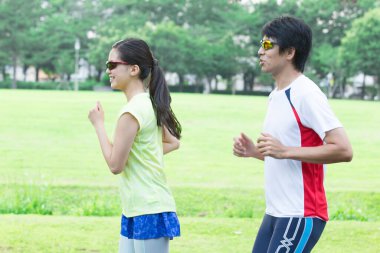 Sportif genç Asyalı çift parkta koşuyor.