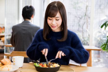 Güzel genç bir kadın Japon restoranında öğle yemeği yiyor.
