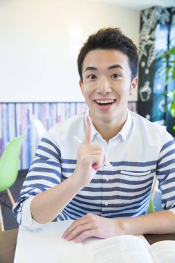 Asyalı öğrenci üniversitede masada okuyor. 