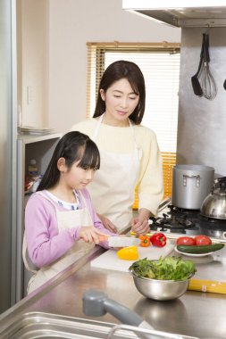 Genç anne ve kız mutfakta taze salata hazırlıyorlar. 